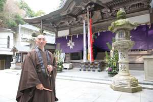 本堂の前に立つ本瀧寺の野間秀顕副住職=大阪府能勢町、滝沢美穂子撮影