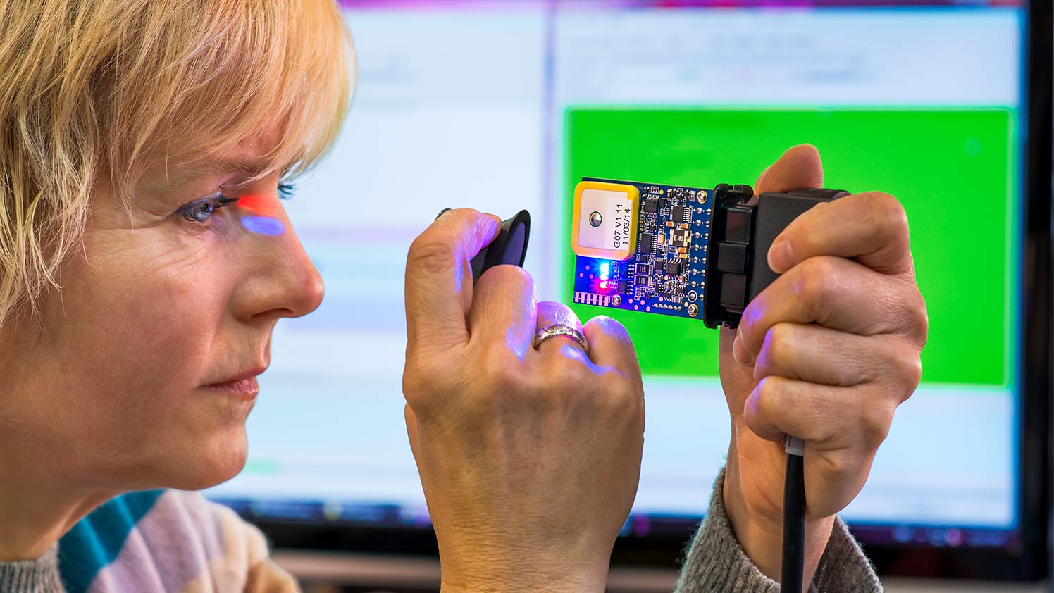 A woman inspects a GO device for quality assurance