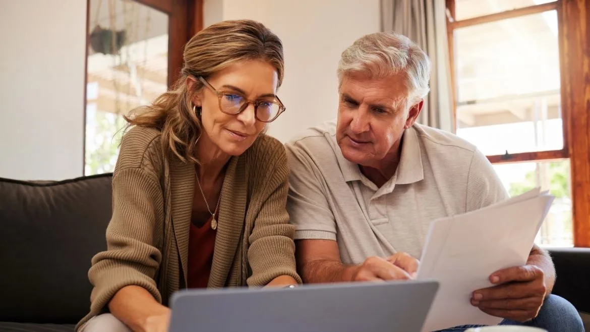 an older couple sitting in front of a computer going over their finances
