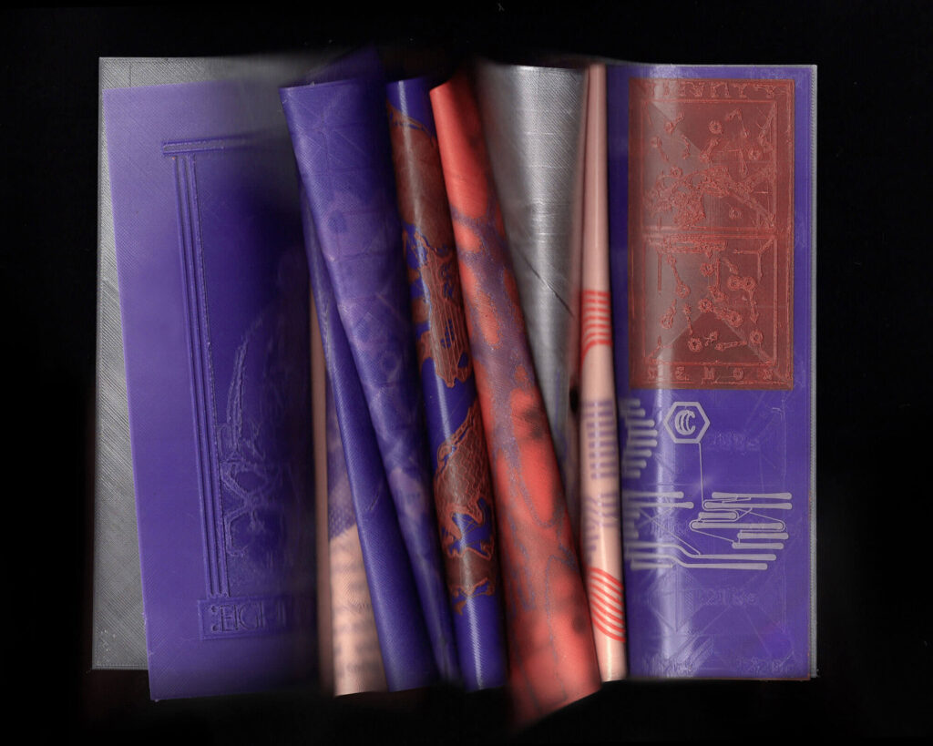 A close-up scan of partially opened, embossed, 3D printed book covers with intricate patterns in shades of purple, red, and silver, creating a layered, textured effect.