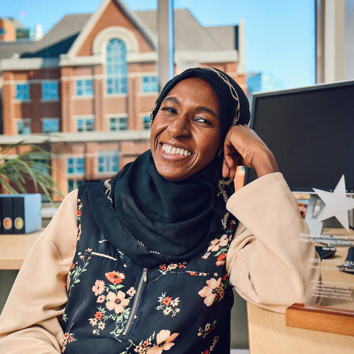A seated woman leans on her left arm and smiles