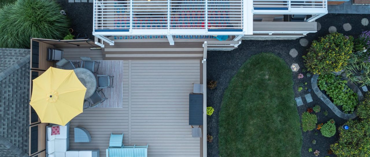 overhead view of backyard composite deck with seating area, yellow umbrella, and covered pergola