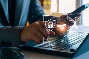 Pessoa sentada a um computador portátil com uma sobreposição ilustrada de informações no ecrã, como o início de sessão no sítio e dados pessoais