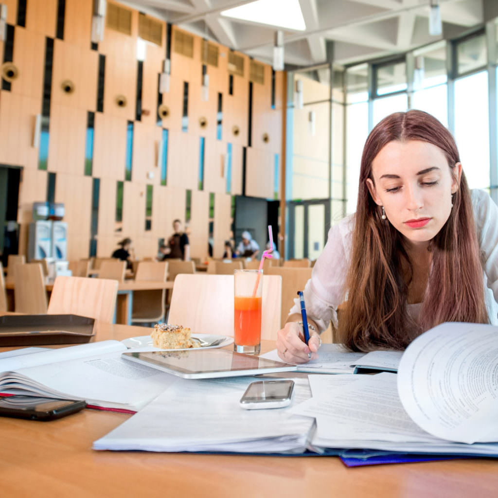 Girl studying in the University canteen with cake