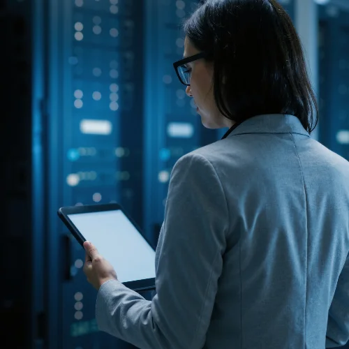 Woman working on tablet inside a server room with Opus Interactives secure cloud technology.