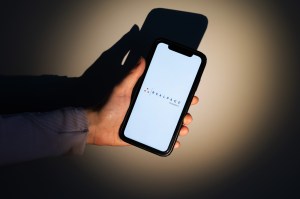 A spotlight shining on a hand holding a phone with the RealPage logo on it.
