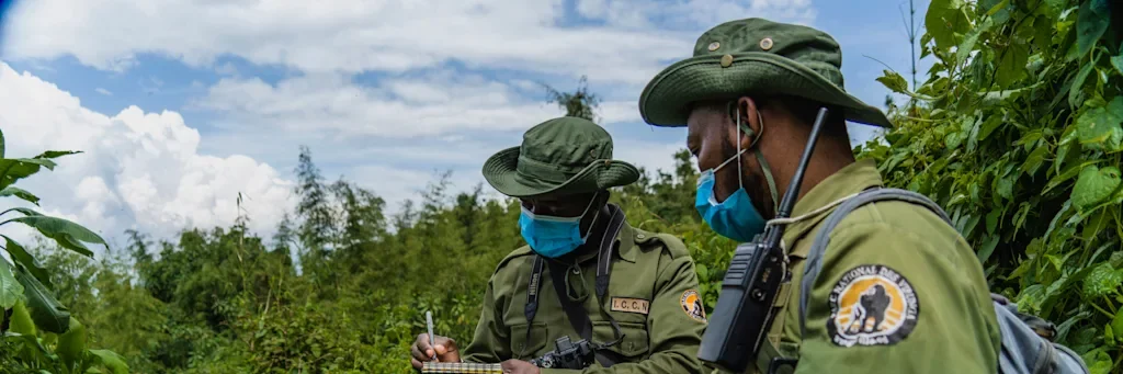 two people outside wearing green uniforms and medical masks
