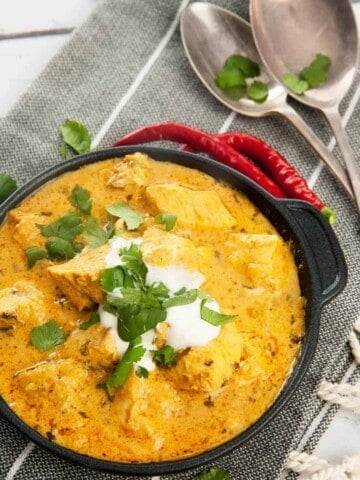 Overhead shot Easy Chicken Curry in black pan with yoghurt and chili