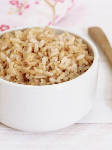 Cooked Brown Rice in a white bowl pink background