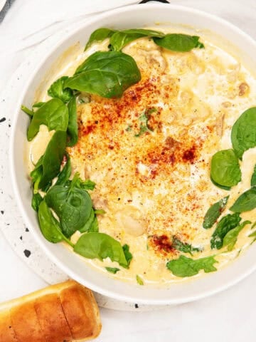 Overhead image of creamy lemon chicken pasta in a large white bowl and garlic bread.